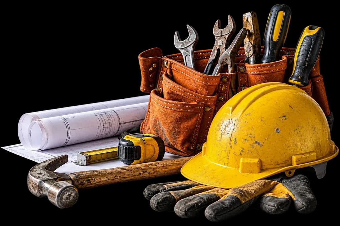 Hard hat, tool belt, hammer, gloves and blueprints